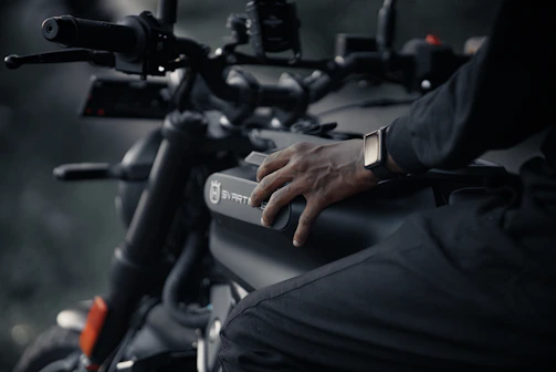 Close-up of hands carefully applying vinyl wrap to a motorcycle tank.