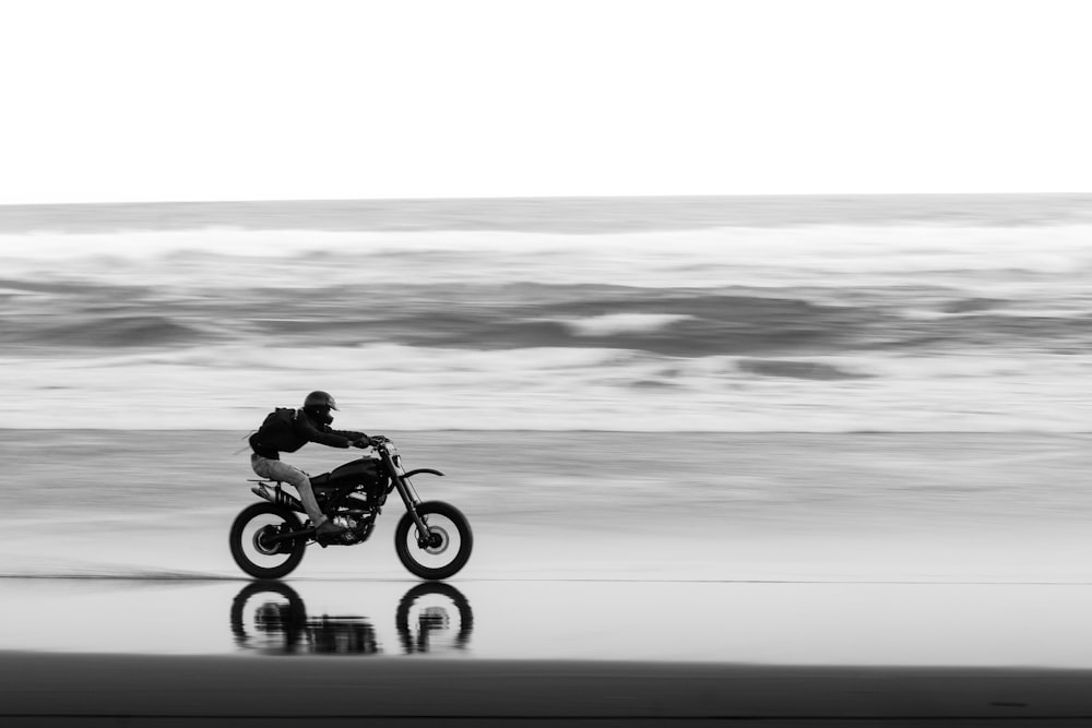 a man riding a motorcycle on top of a beach