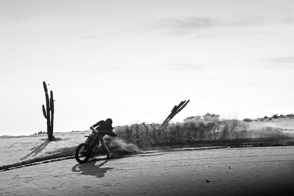 a man riding a motorcycle on top of a sandy beach