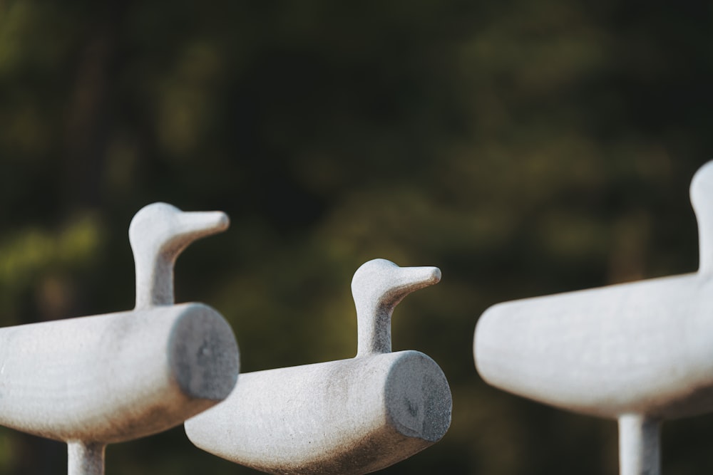 a close up of three cement ducks on a fence