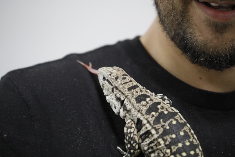 a close up of a person holding a lizard