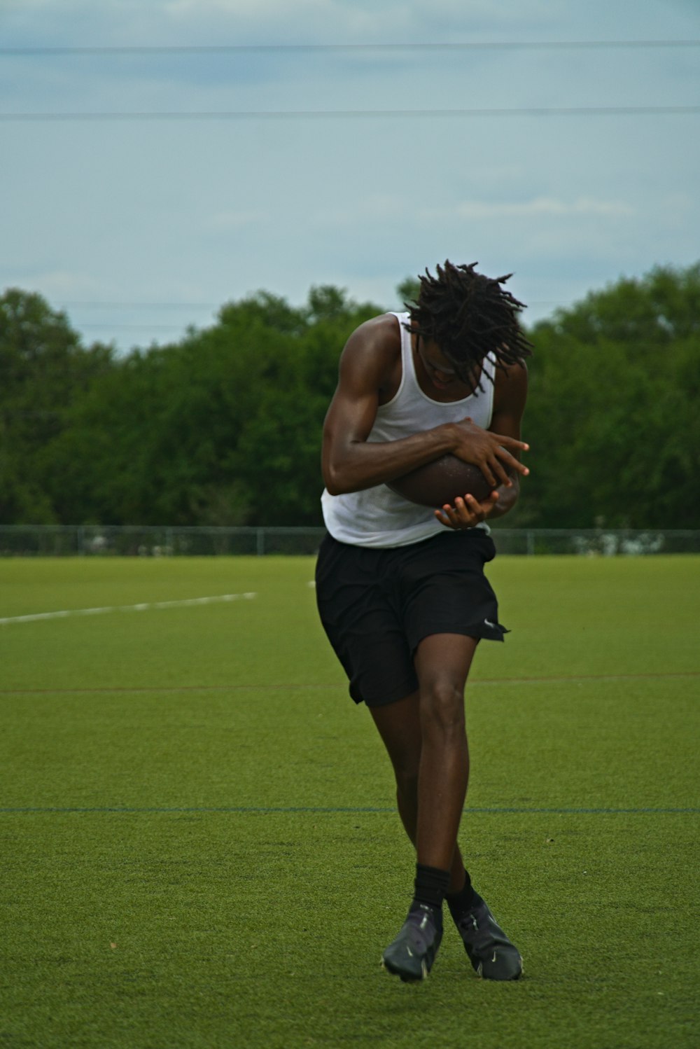 a man holding a ball on top of a lush green field