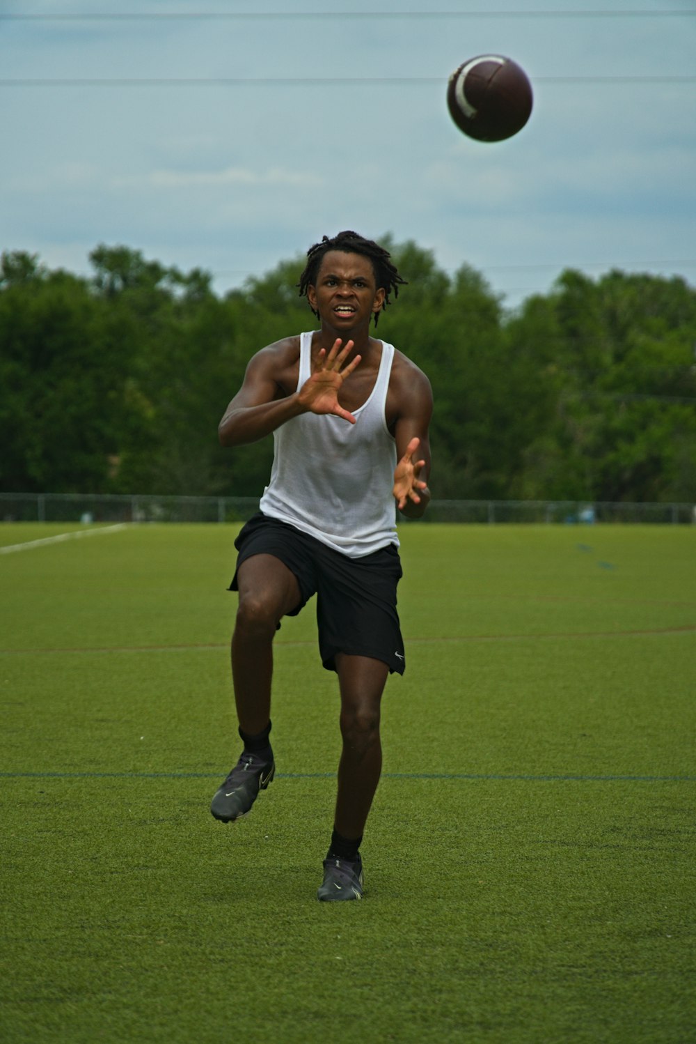 a man in a white tank top is playing frisbee