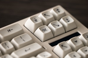 Close-up of a keyboard with arrow symbols on the keys, featuring a light cream color and a smooth texture.