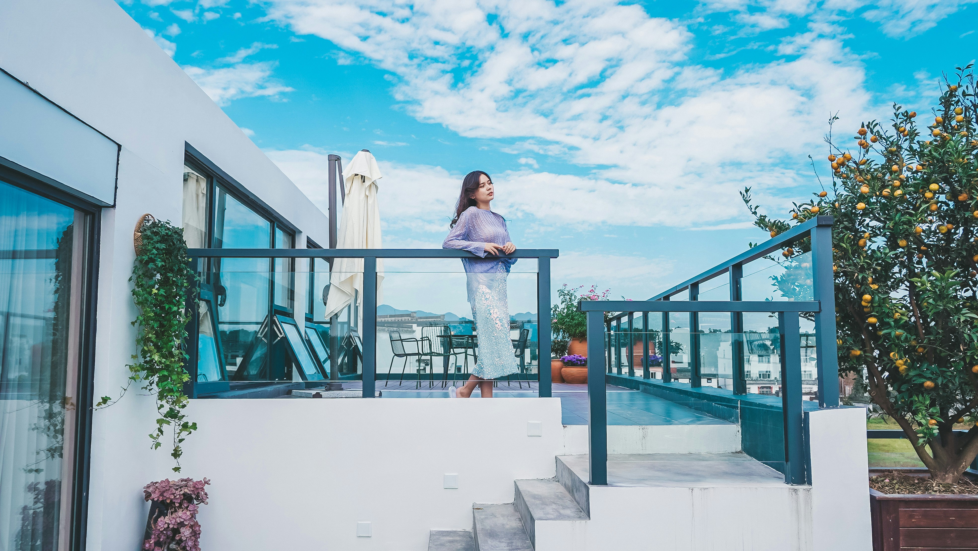 uma mulher em pé em uma varanda ao lado de uma árvore