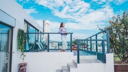 a woman standing on a balcony next to a tree