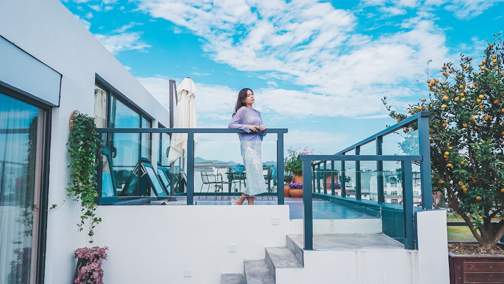 a woman standing on a balcony next to a tree