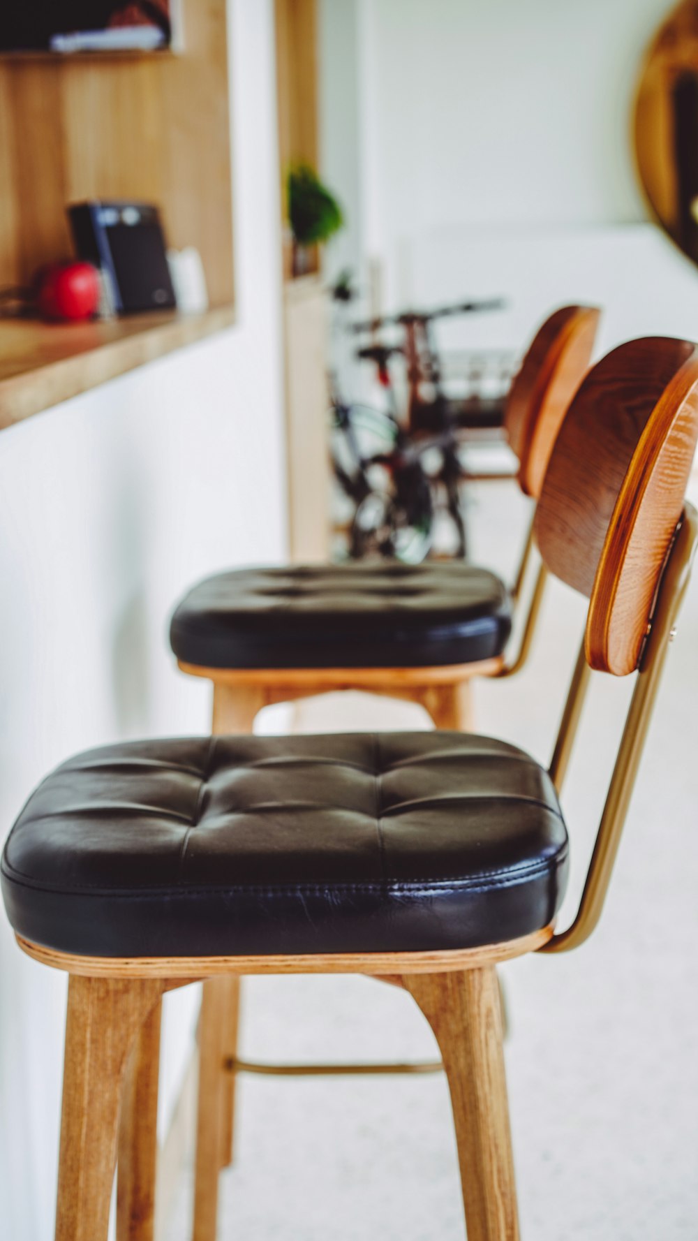 a row of wooden stools with black leather seats