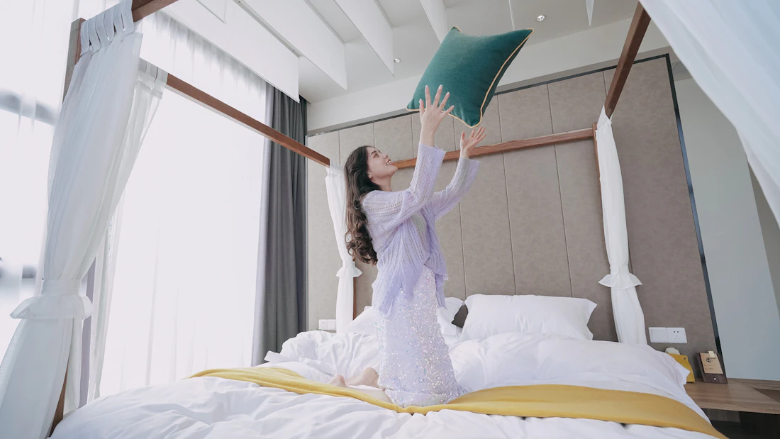 A housekeeper smoothing fresh white linen on a bed