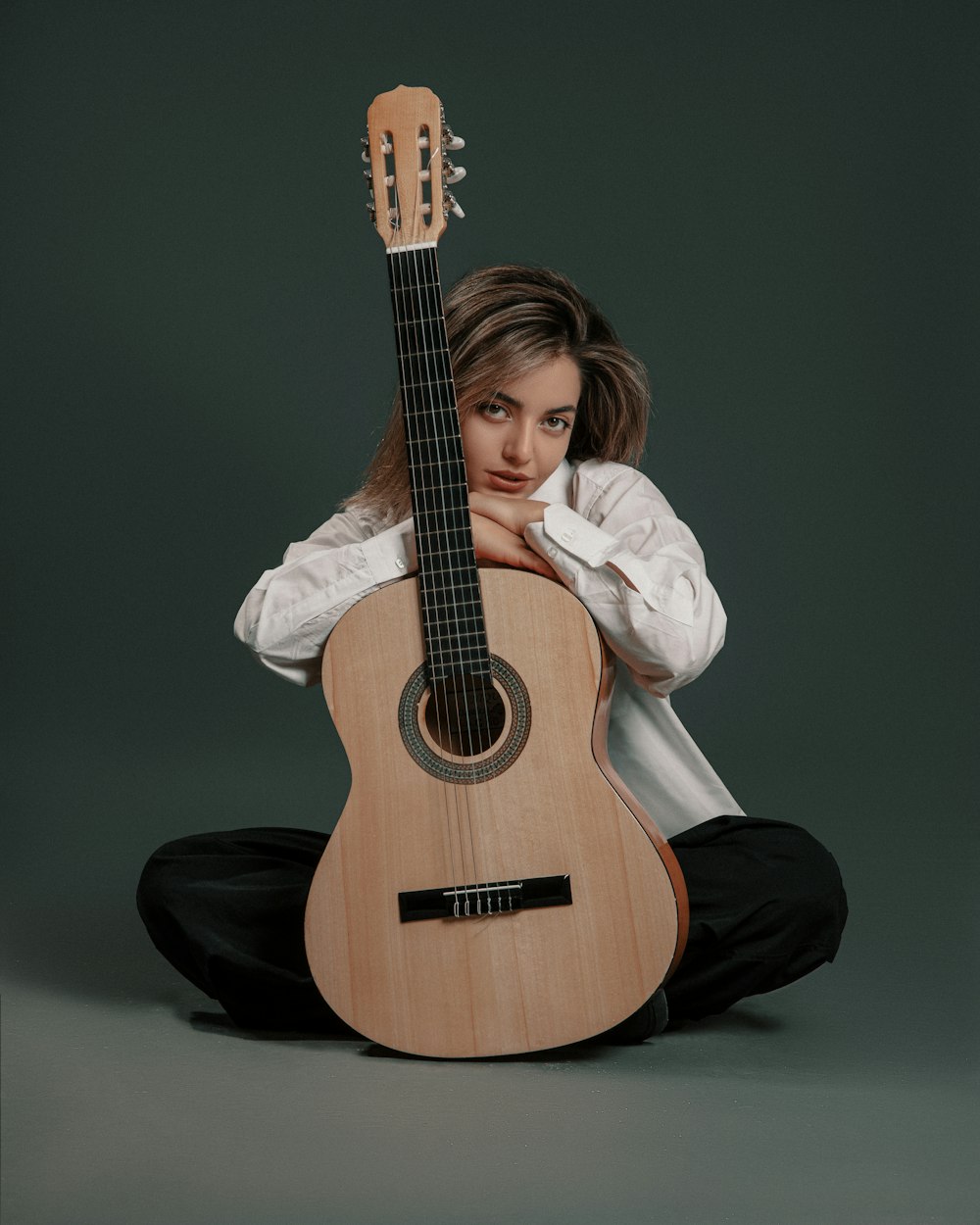 a woman sitting on the floor holding a guitar