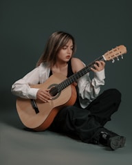 a woman sitting on the ground holding a guitar
