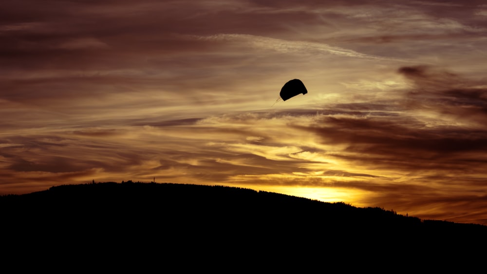 a kite flying in the sky at sunset