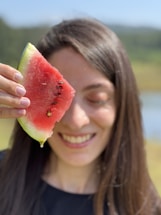A friendly customer service representative holding a watermelon, smiling warmly.