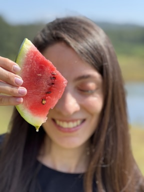 A friendly customer service representative holding a watermelon, smiling warmly.