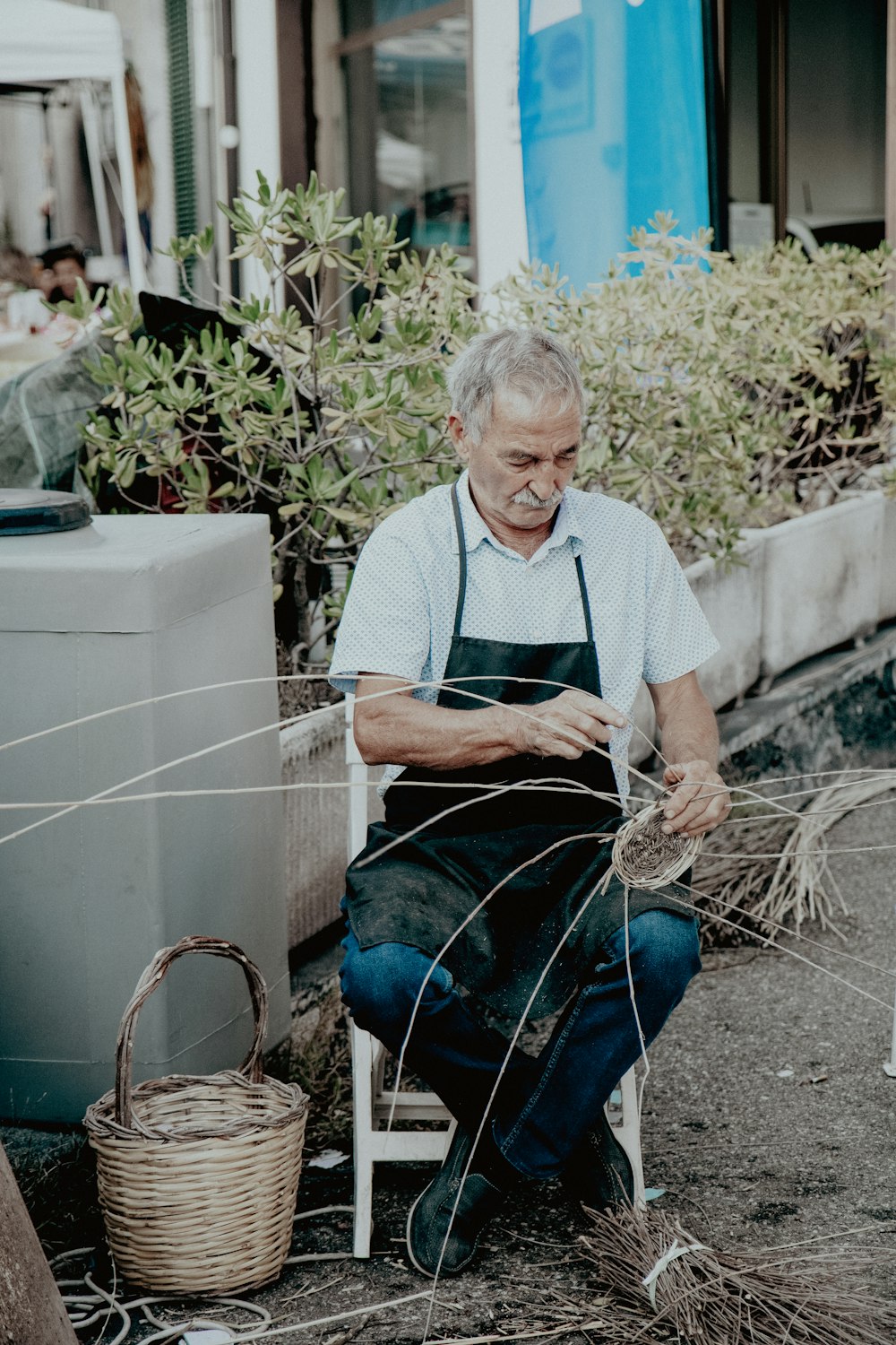 a man sitting on a chair working on a piece of wire