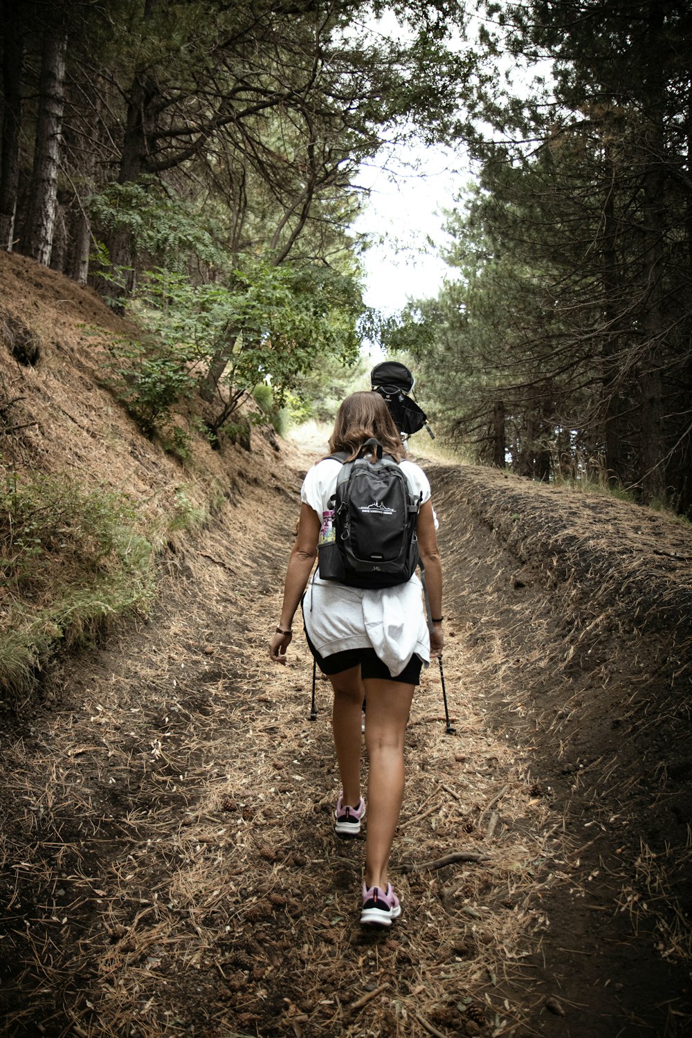 a woman with a backpack walking down a dirt road