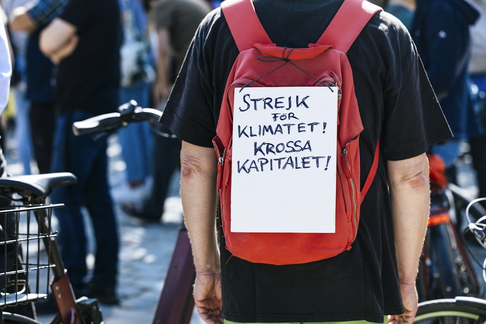 a man wearing a backpack with a sign on it