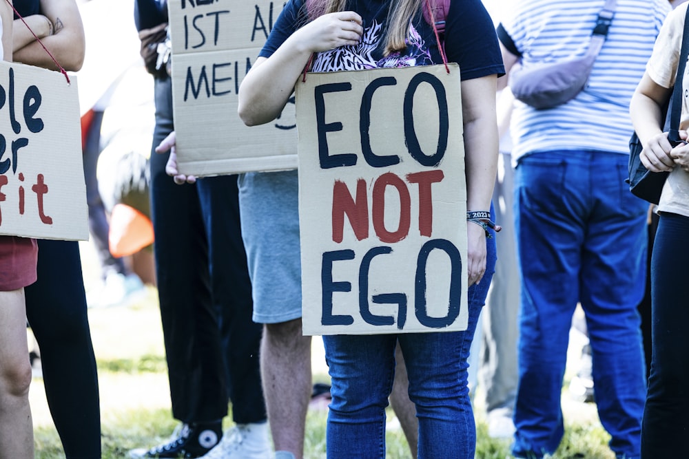 a group of people holding signs that read eco not eco