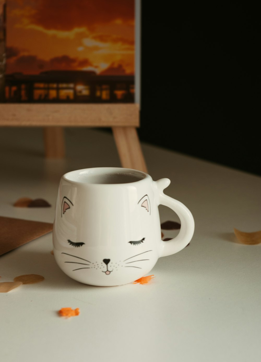 a white coffee cup with a cat face painted on it