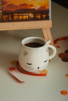 A smooth black ceramic mug with a sleek silhouette of a black cat curled around its side.