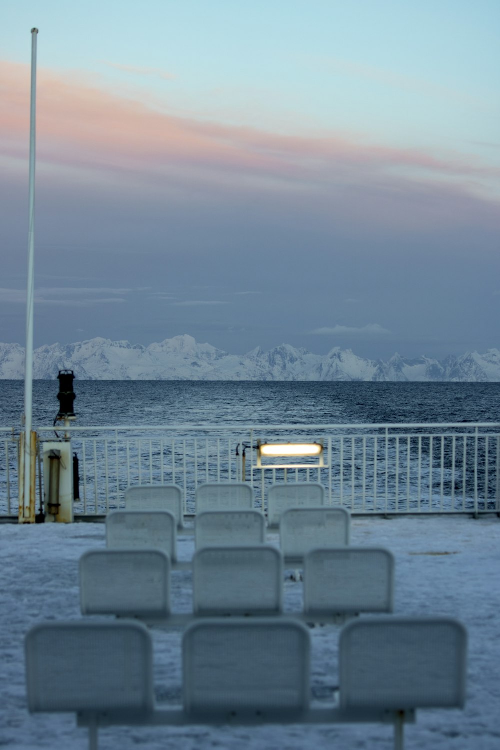 a row of white chairs sitting on top of a snow covered ground