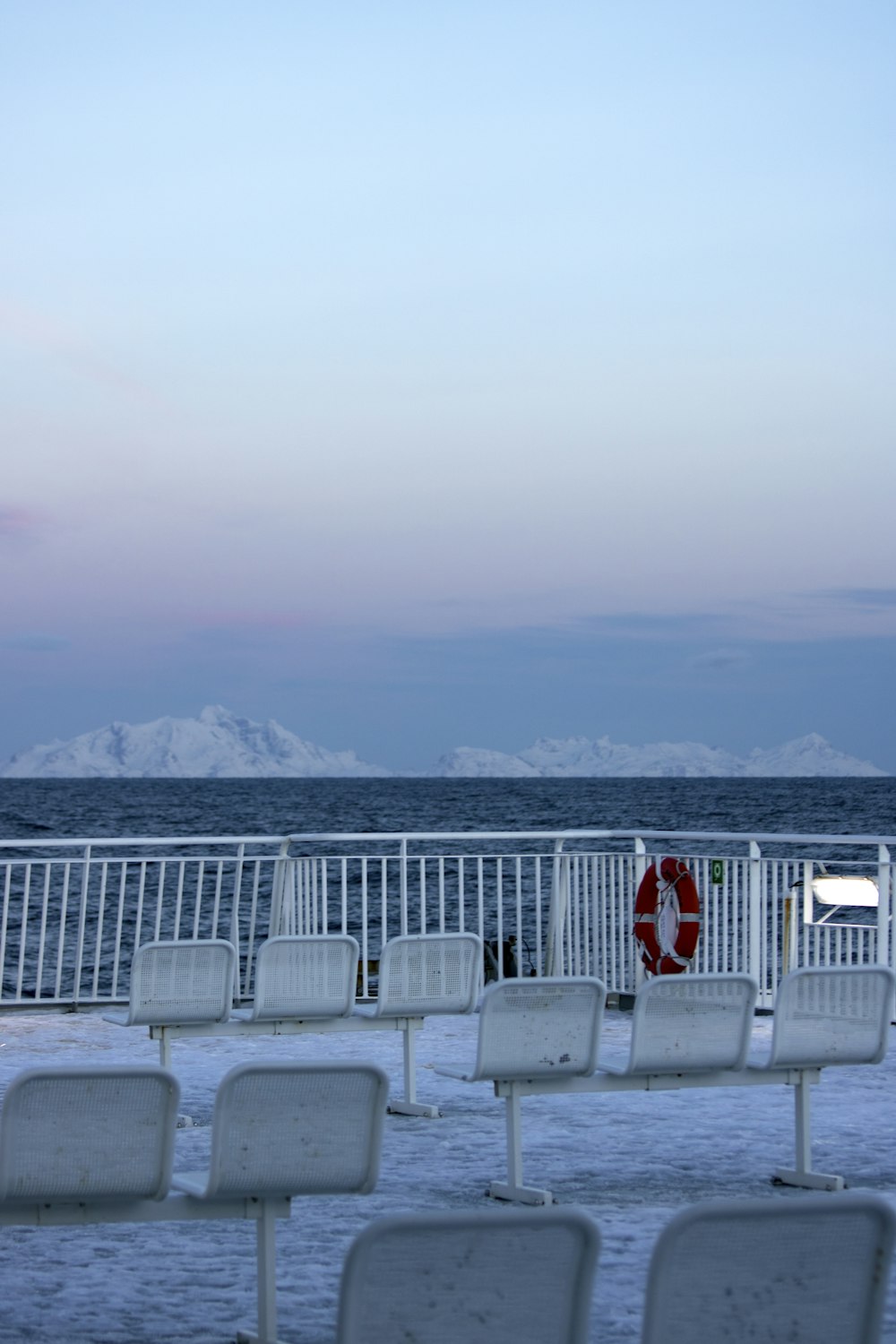 a row of white chairs sitting on top of a beach