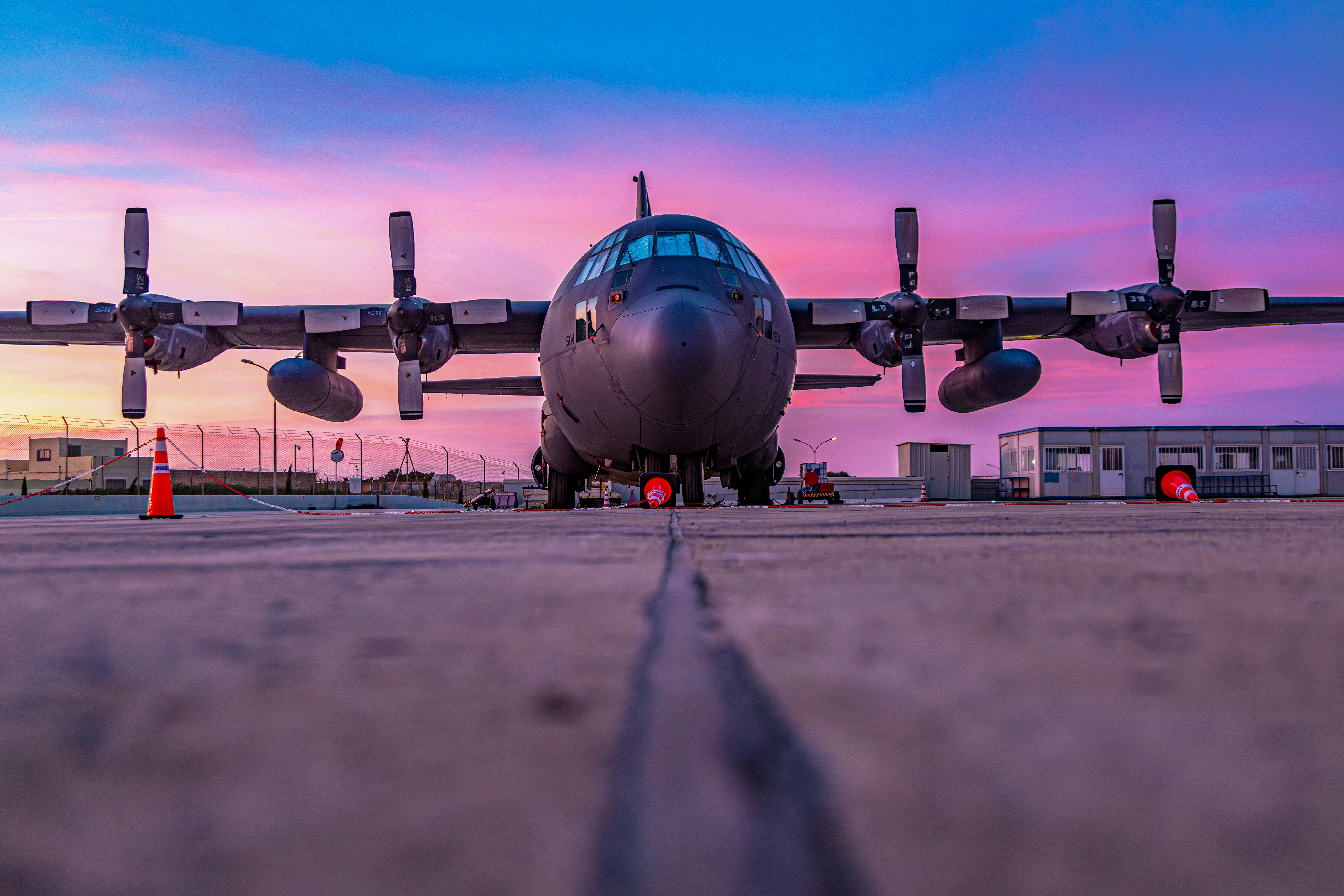 a large jetliner sitting on top of an airport tarmac, LUQA, MALTA SEPTEMBER 23th 2023: A C-130 Hercules military plane is parked from the runway at malta International Airport