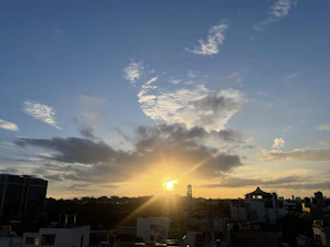 A clear sky with gentle clouds over a peaceful cityscape at sunrise.
