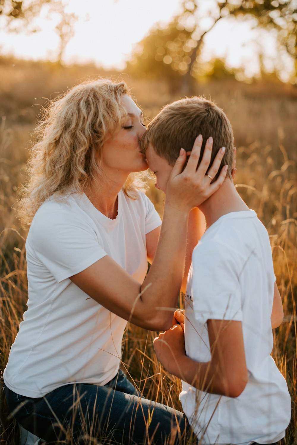 a woman kissing a boy in a field