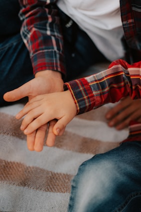 A warm scene of a parent and child holding hands, both wearing shirts with matching child-drawn prints