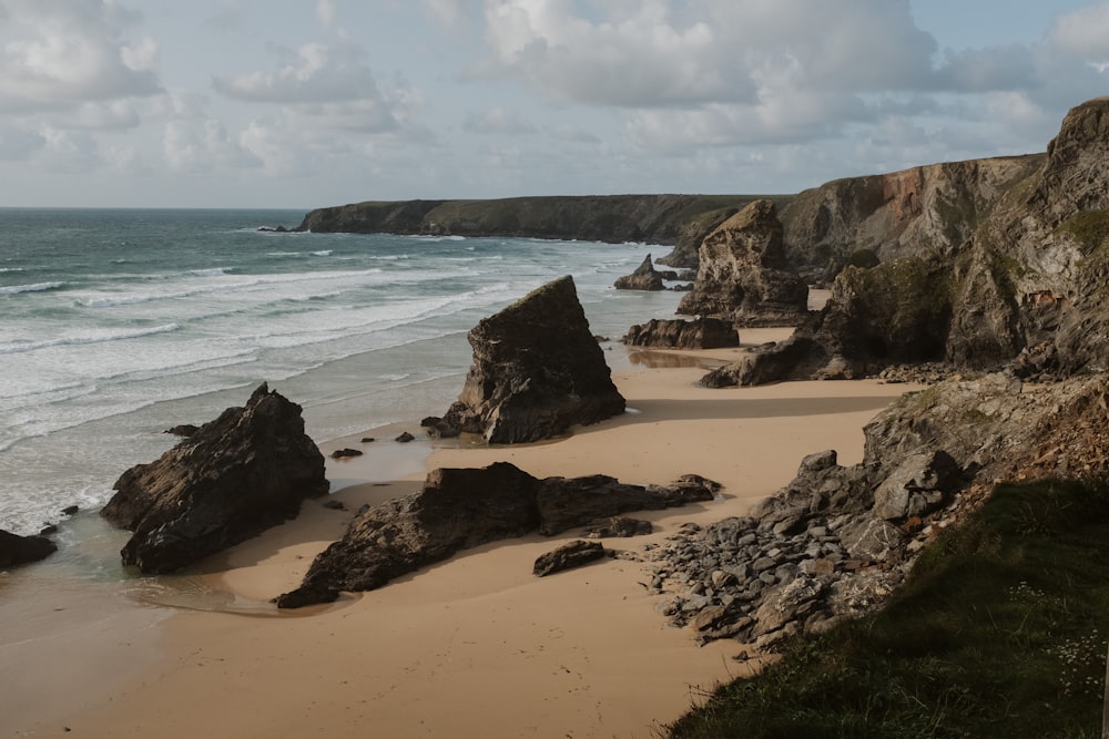 a sandy beach next to the ocean under a cloudy sky