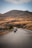 A group of motorcyclists riding along a scenic mountain road with lush greenery in the background.