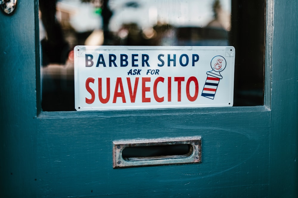Eine blaue Tür mit einem Schild mit der Aufschrift Barber Shop Ask for Suavecit