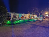 Elegant outdoor event setup with white chairs and a modern tent under soft evening lighting