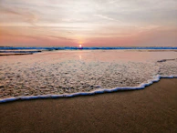 A serene beach at sunset with gentle waves and warm light.