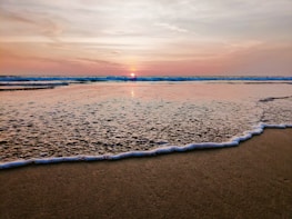 A serene sunset over a quiet beach with gentle waves.