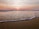 A serene beach at sunset with gentle waves lapping the shore.