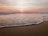 A serene beach at sunset with gentle waves lapping the shore.