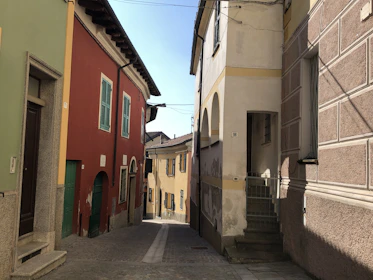 A scenic view of a sunlit Spanish village street lined with colorful buildings and cobblestones.