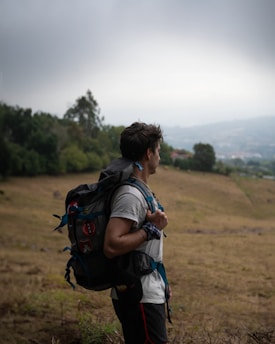 a man with a backpack is standing in a field