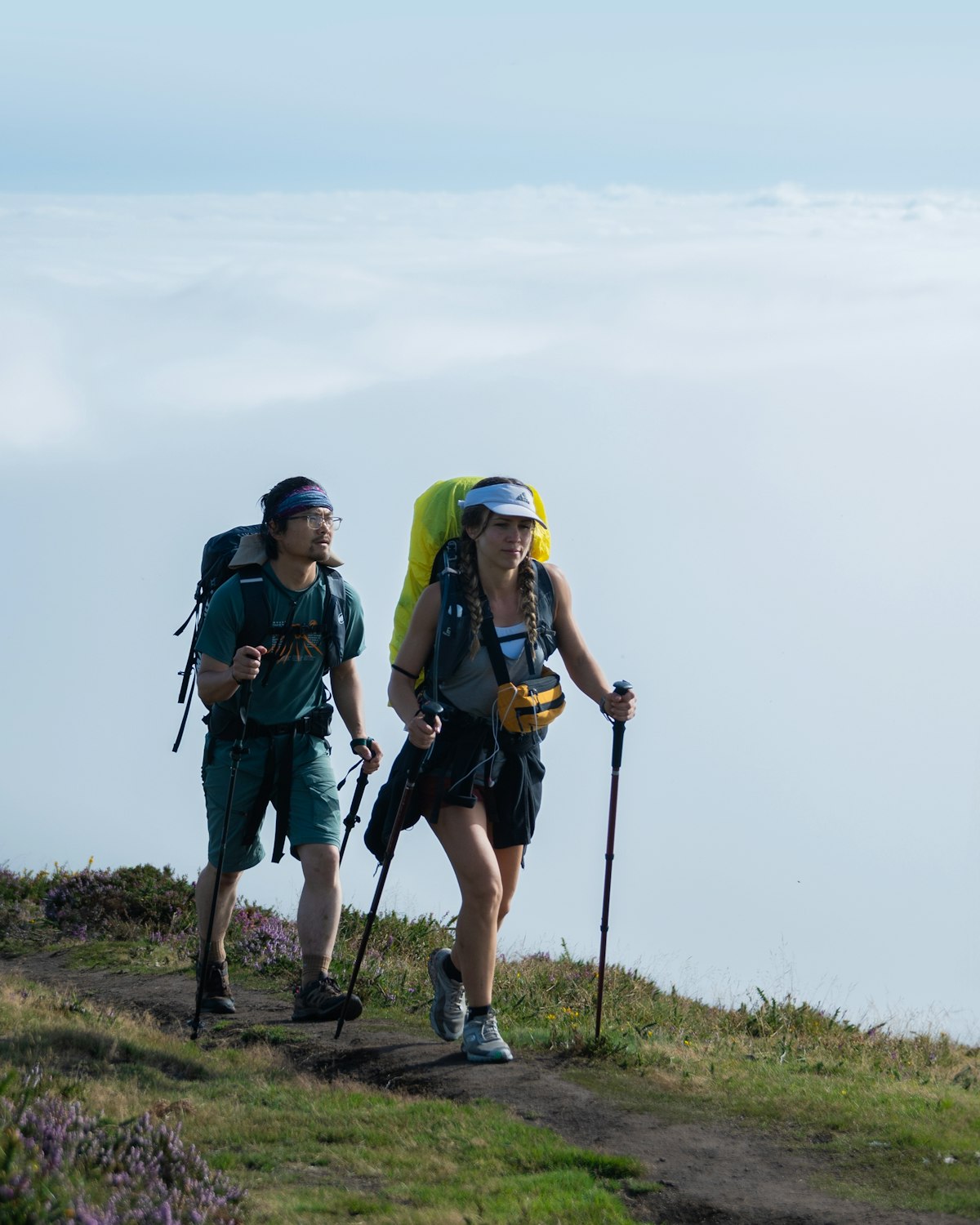 Dos peregrinos con mochila caminando entre niebla en una etapa de montaña