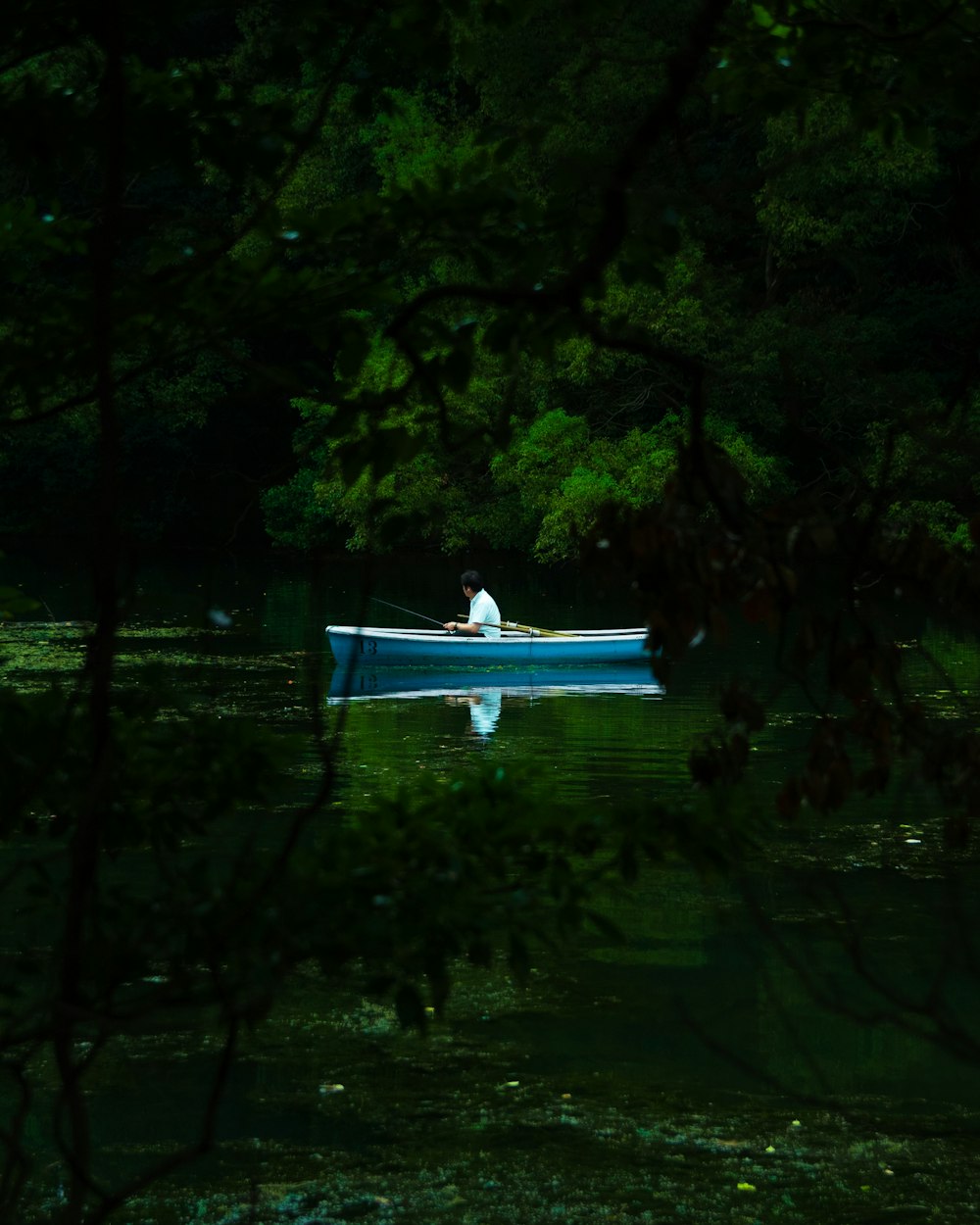 a man in a blue row boat on a lake