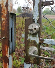 Technician performing maintenance on a metal gate lock.