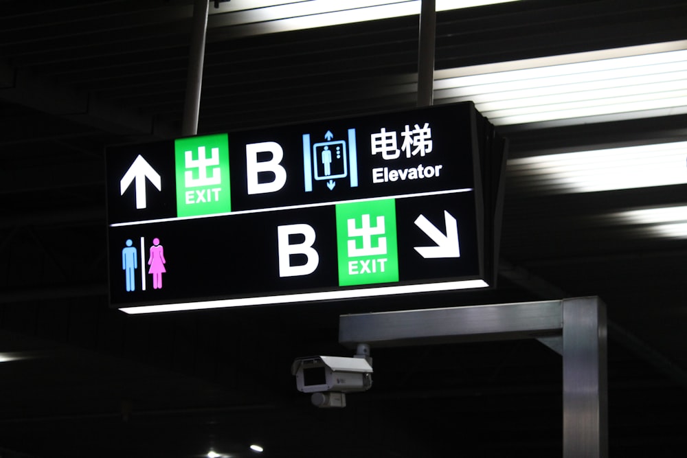 a black and green airport sign hanging from a ceiling
