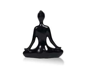 Close-up of a delicate meditation sculpture with subtle shadows highlighting its smooth contours against a charcoal background.