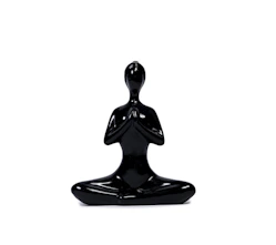 a black statue of a person sitting in a yoga position