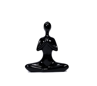 A sleek, black sculpture of a human figure seated in a meditative pose with hands in a prayer position. The figure is minimalist, with smooth surfaces and an abstract design, emphasizing calmness and balance.