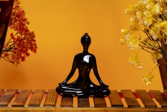 a black buddha statue sitting on top of a wooden table