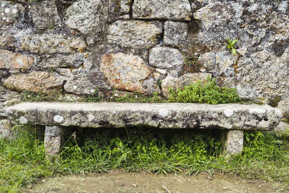 a stone bench sitting in front of a stone wall