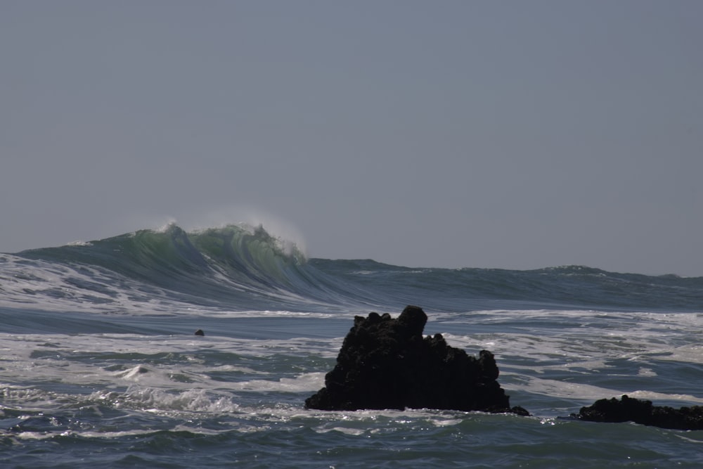 Eine große Welle bricht über einen Felsen im Ozean